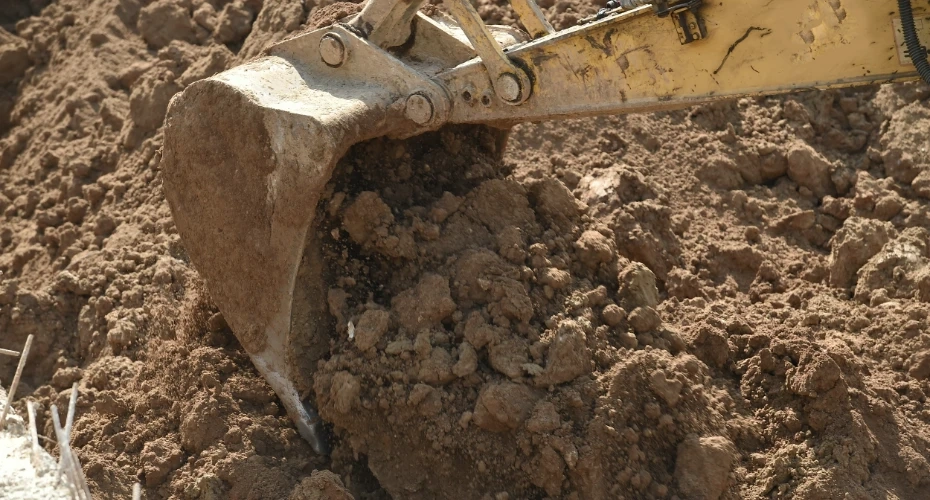 Łyżka koparki wykonująca wykop w ziemi – prace ziemne i roboty wykopowe